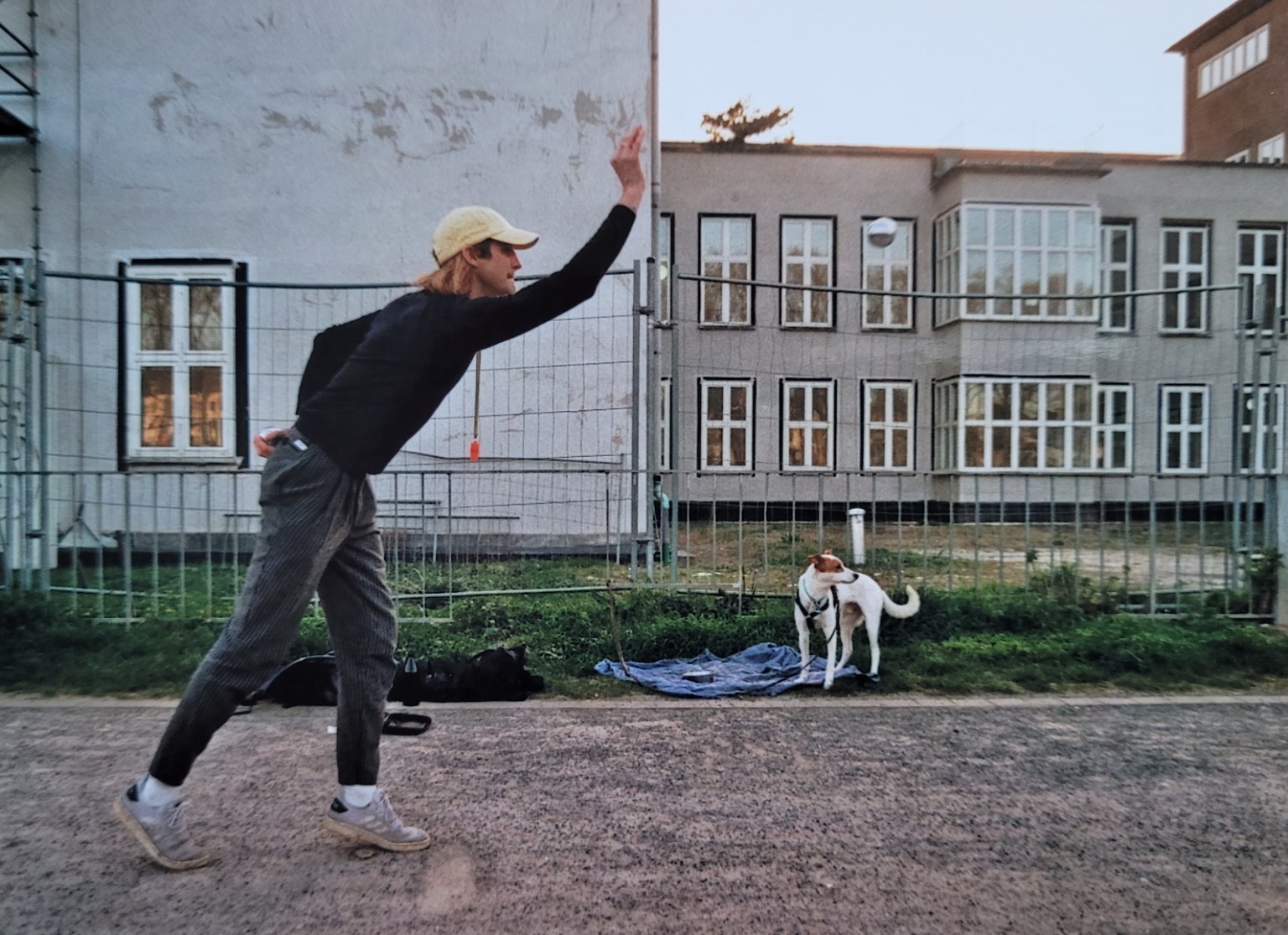 Person in einer Wurfbewegung neben einem Hund