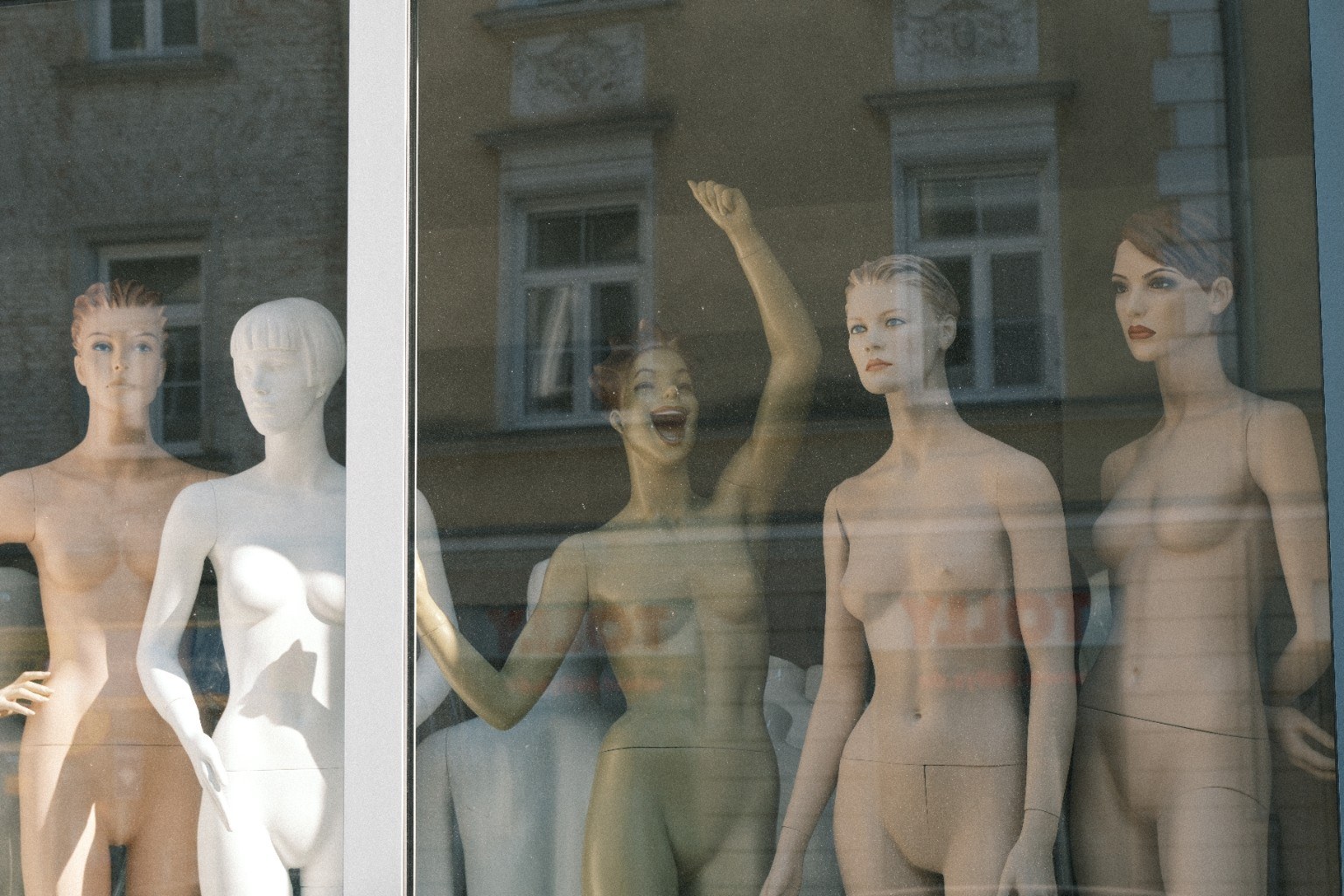 Schaufensterpuppen hinter spiegelnder Scheibe