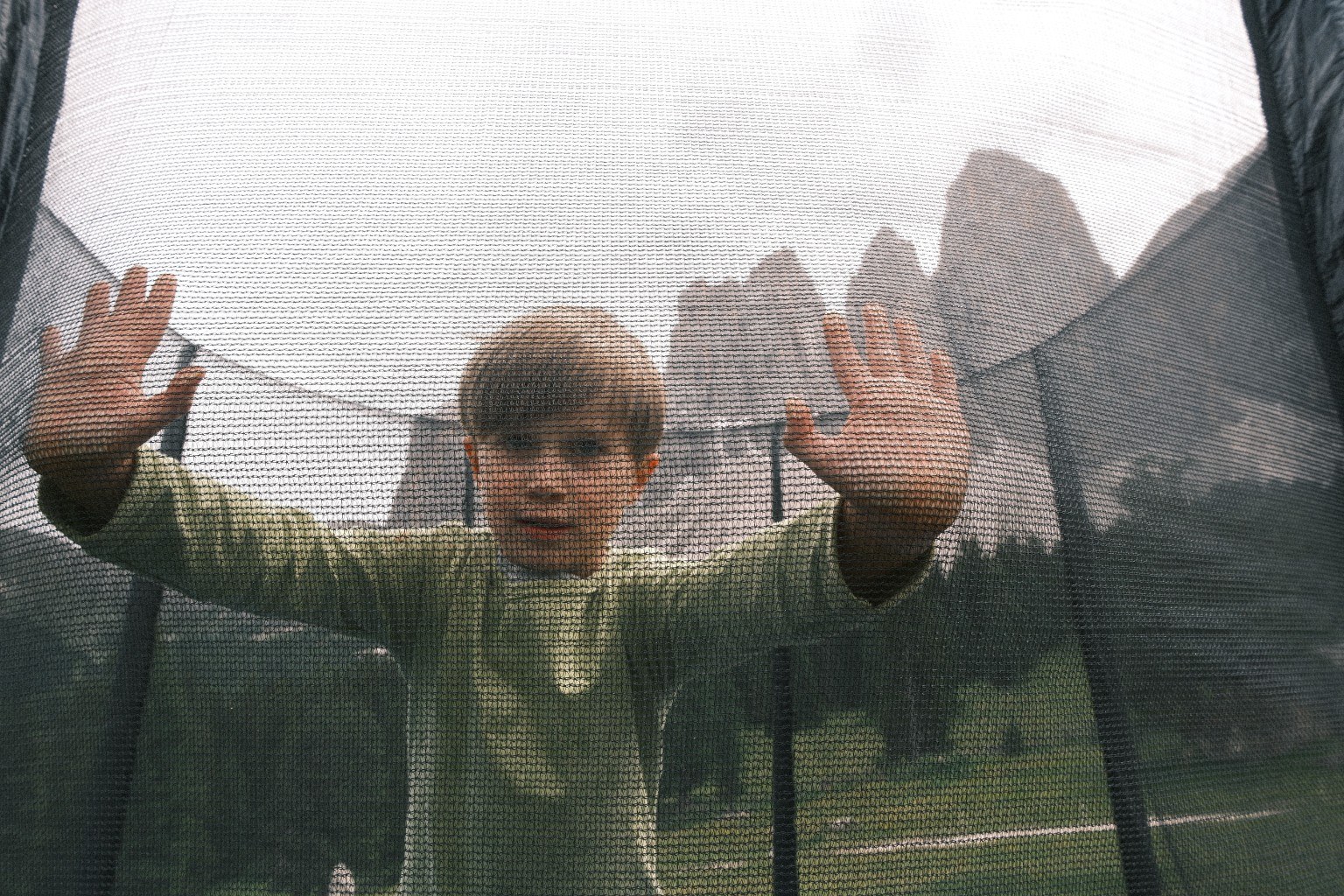 Kind hinter einem Trampolinnetz