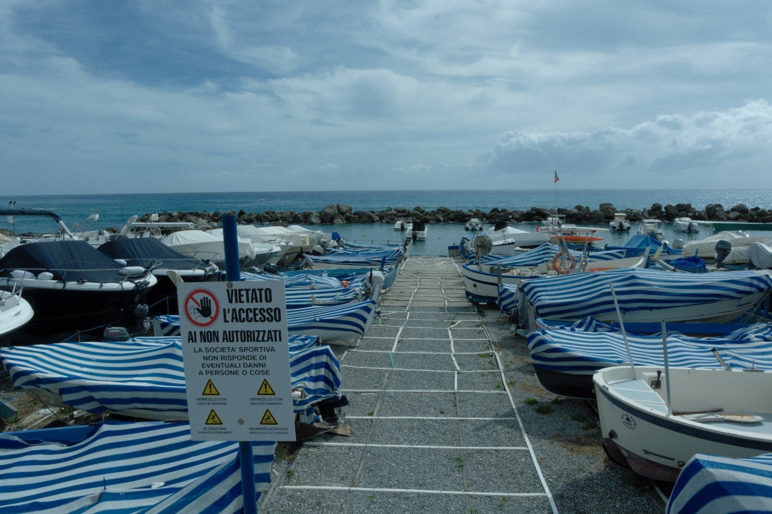 Kleiner Hafen mit blau-weiß abgedeckten Booten