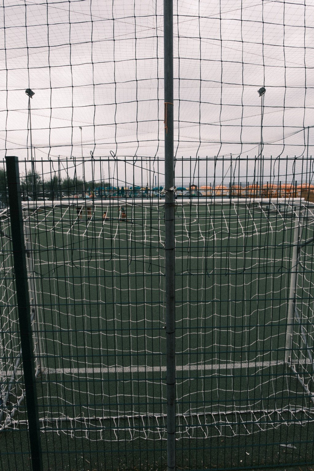 Fußballplatz hinter mehreren Netzen und Zäunen