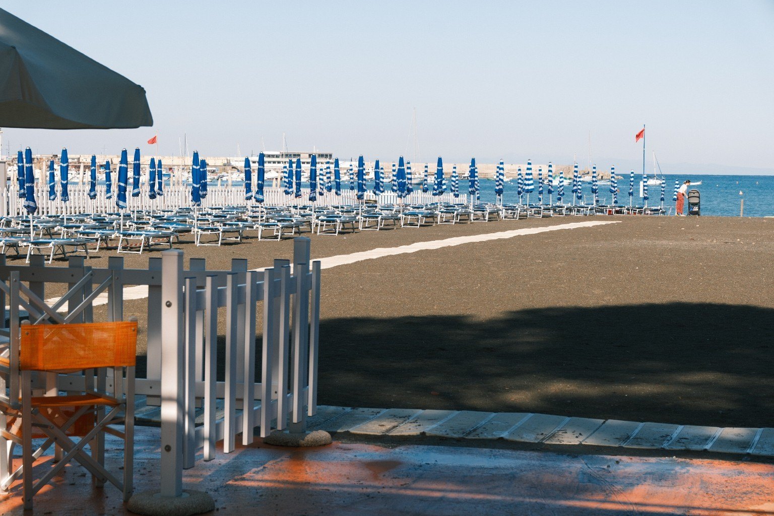 Strand mit Reihen geschlossener blau-weißer Schirme
