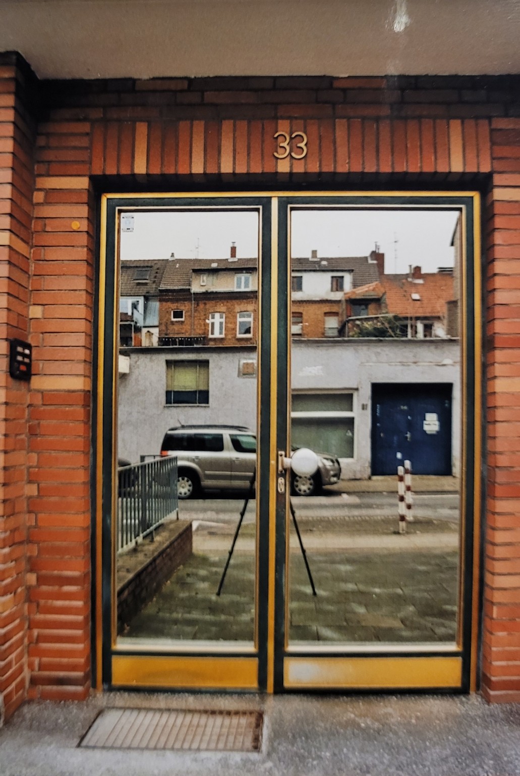 Eingangstür mit Spiegelung der Straße und Hausnummer 33