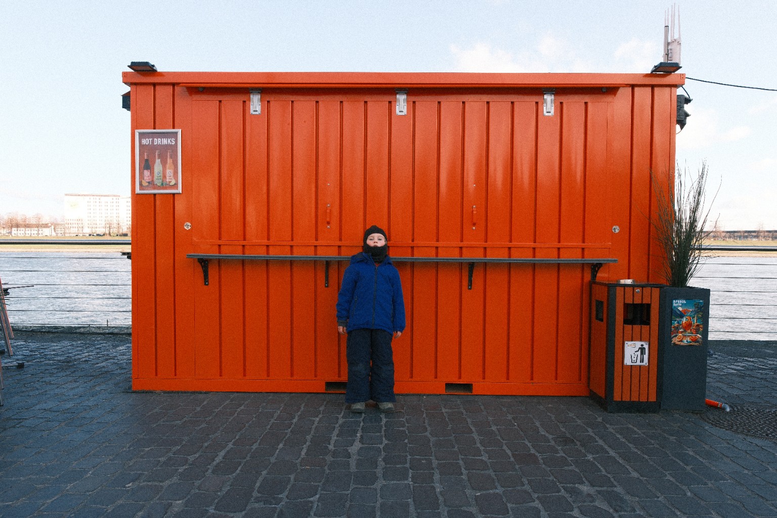 Kind vor einer orangefarbenen Wand am Wasser